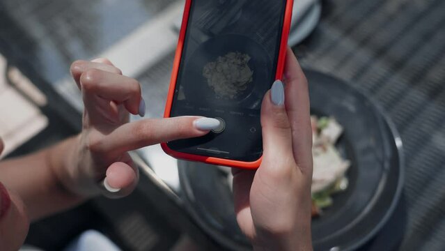 Woman photographing food on summer holidays, adjusting brightness on smartphone before taking street food photo
