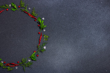 Wreath of fresh parsley and dill, chili pepper, sea salt on dark stone concrete background