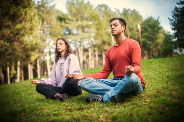 Naklejka na ściany i meble Young couple in everyday casual clothing doing yoga relax exercise in nature park outdoor