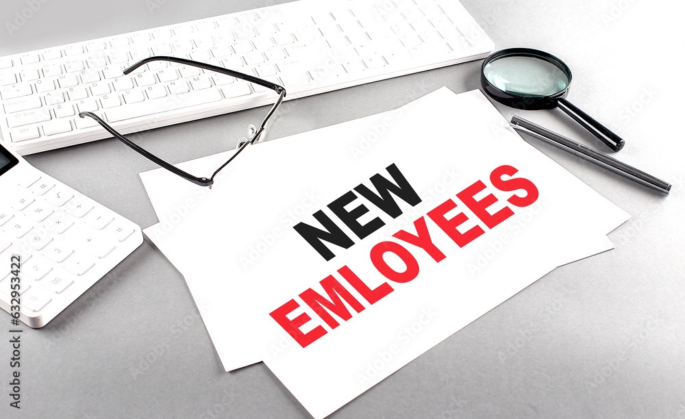 Poster new employees text on a paper on a gray background near a calculator and a white keyboard