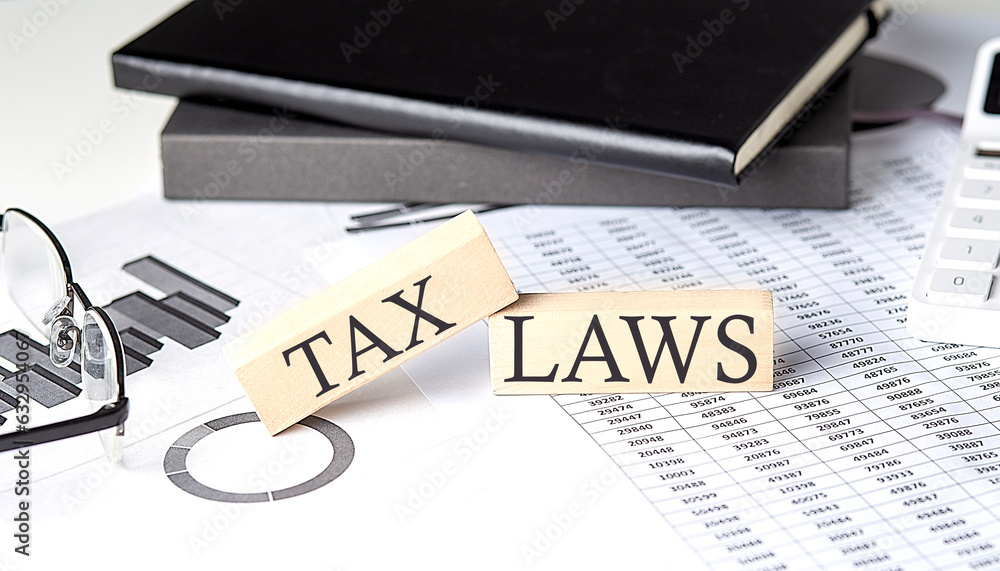Poster tax laws - text on a wooden block with chart and notebook