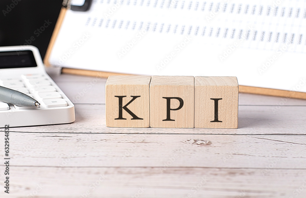 Poster kpi word on a wooden block with clipboard and calcuator