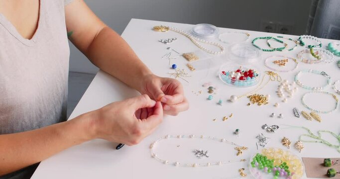 Female jewelry designer working in studio making necklace and earrings