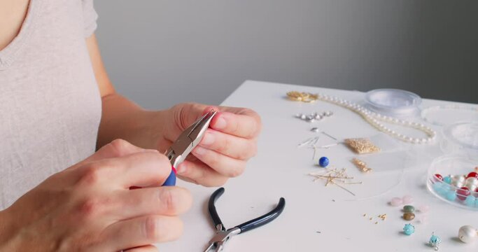 Female jewelry designer working in studio making necklace and earrings