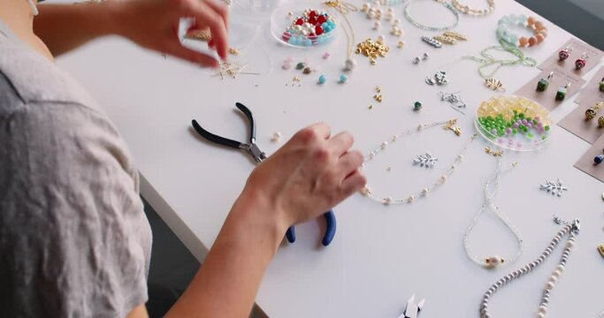 Female jewelry designer working in studio making necklace and earrings