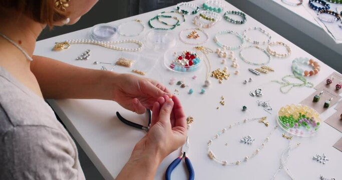 Female jewelry designer working in studio making necklace and earrings