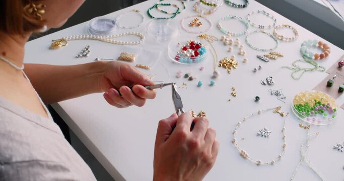 Female jewelry designer working in studio making necklace and earrings