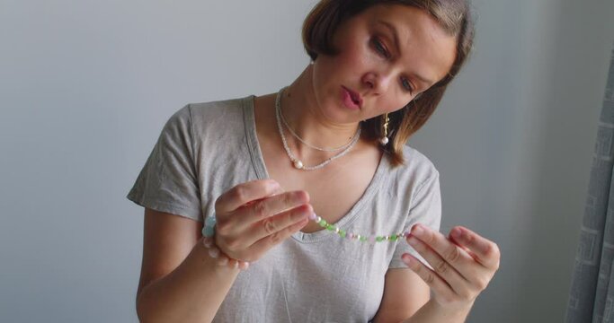 Female jewelry designer working in studio making necklace and earrings