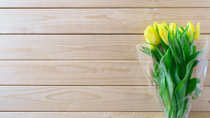Yellow tulips bouquet on wooden background with copy space