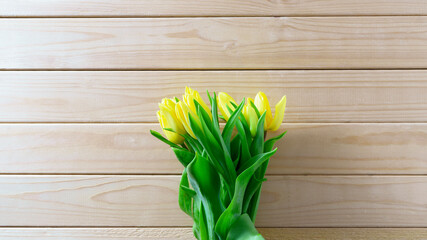 Yellow tulips bouquet on wooden background with copy space