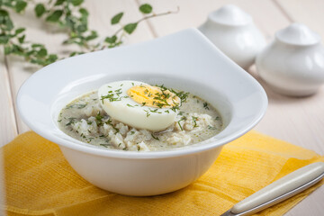Sorrel soup with egg in white bowl.