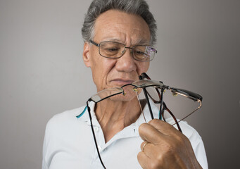 Mature Man checking out and holding up all his old prescription glasses