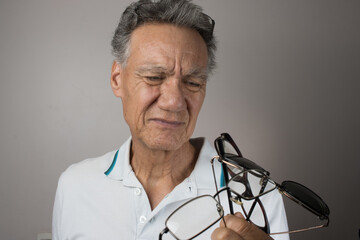 Mature Man checking out and holding up all his old prescription glasses