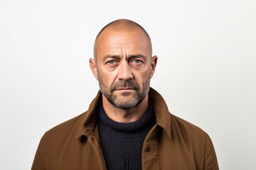 Lifestyle portrait photography of a man in his 40s with furrowed brows and a tense expression due to hypertension wearing a chic cardigan against a white background 