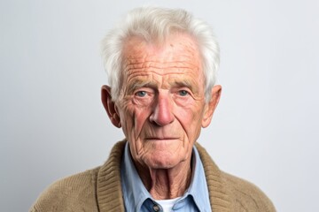 Medium shot portrait photography of a man in his 80s with furrowed brows and a tense expression due to hypertension wearing a chic cardigan against a white background 