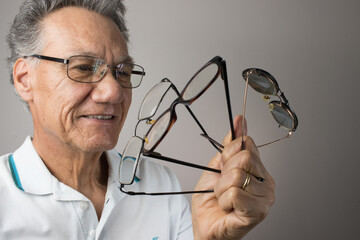 Mature Man checking out and holding up all his old prescription glasses