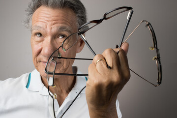 Mature Man checking out and holding up all his old prescription glasses