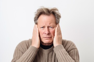 Group portrait photography of a man in his 50s pressing his temple due to a migraine wearing a chic cardigan against a white background 