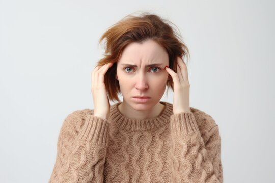 Medium shot portrait photography of a woman in her 30s appearing weakened and pale because of anemia wearing a cozy sweater against a white background 