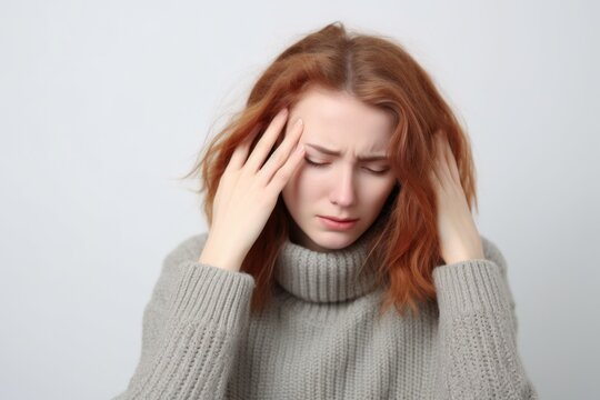 Medium shot portrait photography of a woman in her 30s appearing weakened and pale because of anemia wearing a cozy sweater against a white background 