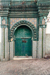 An ornamented gate in moorish style with geometric islamic patterns and  house painted white at...