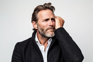 Lifestyle portrait photography of a man in his 40s cupping his ear in pain due to an ear infection wearing a chic cardigan against a white background 