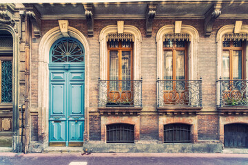Facade or exterior of historic traditional house in orange  with blue gate in the old city of Toulouse, France