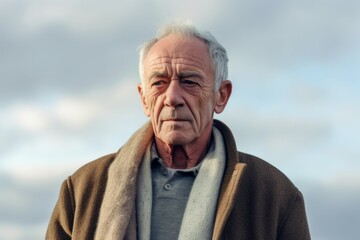 Medium shot portrait photography of a man in his 70s with a hint of fatigue due to chronic kidney disease wearing a chic cardigan against a sky background 