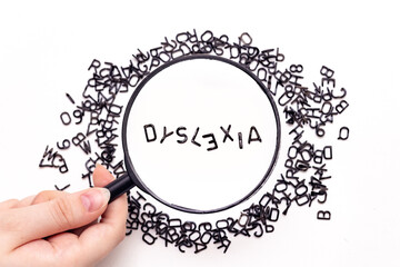  Dyslexia disorder, Random small letters on white background, the word Dyslexia close-up under a magnifying glass