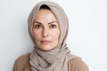 Lifestyle portrait photography of a woman in her 40s showing tiredness and a worn-down expression due to chronic fatigue syndrome wearing hijab against a white background 