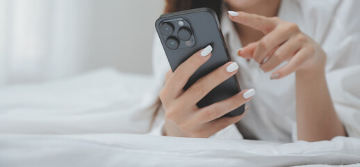 Obraz premium Happy young female in casual clothes smiling and looking at camera while using laptop on bed in bedroom at home