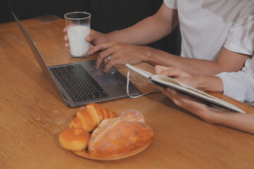 Handsome man sitting near his wife at kitchen. Family couple see social media, surf the web while sitting at kitchen table with generic laptop. Couple working with laptop at home
