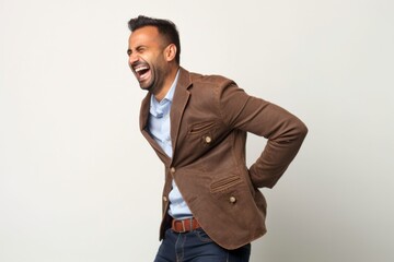 Fototapeta premium Medium shot portrait photography of a man in his 30s wincing with pain and holding his lower back due to sciatica wearing a chic cardigan against a white background 