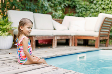Funny cute girl on summer vacation. The child has fun near the pool. Cute baby girl in a colorful...