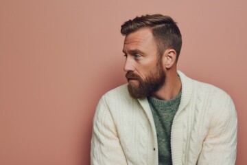 Fototapeta premium Lifestyle portrait photography of a man in his 30s with a somber and deeply sad expression due to major depression wearing a chic cardigan against a pastel or soft colors background 