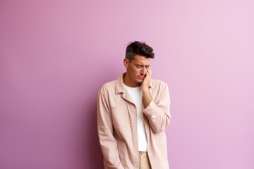 Group portrait photography of a man in his 20s visibly in discomfort and fatigue from an autoimmune disease like lupus wearing a trendy jumpsuit against a pastel or soft colors background 