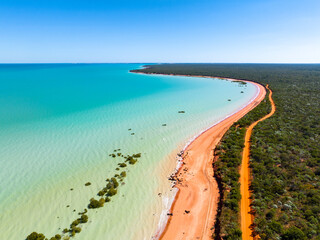 Aerial view of red sandy coastline along turquoise water at Red Sand Beach, Roebuck Bay, Broome, Western Australia