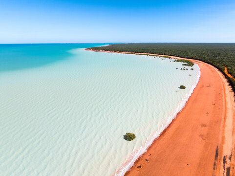Aerial view of red sandy coastline along turquoise water at Red Sand Beach, Roebuck Bay, Broome, Western Australia