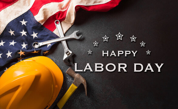 Happy Labor day concept. American flag and different construction tools with the text on dark background.