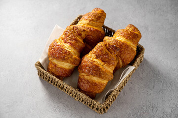 Croissants in a basket, freshly baked sweet pastry on gray background