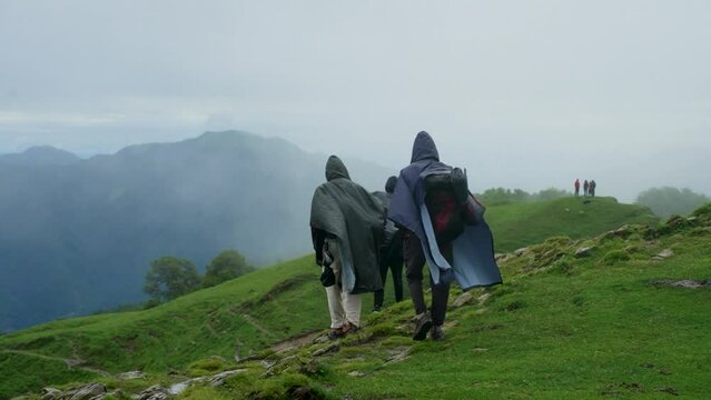 A group of three modern tourists backpackers travels in the summer along in Ali Bugyal, Uttarakhand, India. 