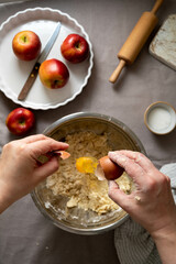 Homemade apple pie pastry. Cooking process, female hands adding eggs to dough for pie.
