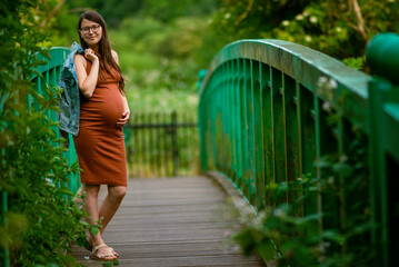 Caucasian Young Pregnant woman Tummy belly summer green  bridge touching stomach field expecting...