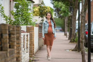 Beautiful young pregnant woman belly london smiling confident  city street outdoors walk urban cityscape 9 months smiling Active mom Brunet caucasian  summer glasses brown Tight dress Tummy