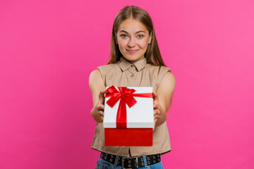 Fototapeta premium Positive smiling young woman presenting birthday green gift box stretches out hands, offer wrapped present career bonus, celebrating party, sale. Blonde girl isolated alone on pink studio background