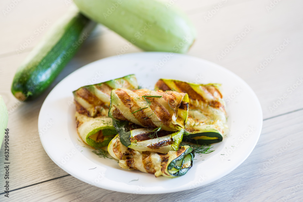 Sticker Grilled zucchini pieces with garlic sauce in a white plate.