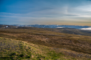 Beautiful tundra landscape with dry grass, some snow and fog in the valleys