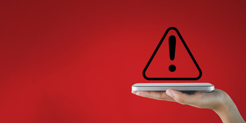 Safety, hazard,caution, danger,Digital Crime,Cyber Security, information security,data protection concept.,Hand holding smartphone with Exclamation mark or Warning sign over red background.