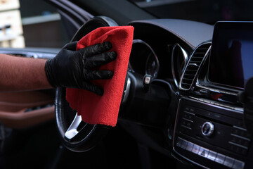 Cleaning car interior.Steering wheel of car is wiped with napkin. Concept of cleanliness and disinfection.