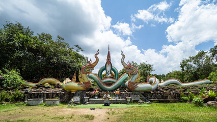 Ubon Ratchathani, THAILAND - August 8, 2023: Buddhist travel glowing serpent statue with sunlight at Wat Pa Phu pang temple, Si Chiang Mai District, Ubon Ratchathani Province, Thailand. - obrazy, fototapety, plakaty